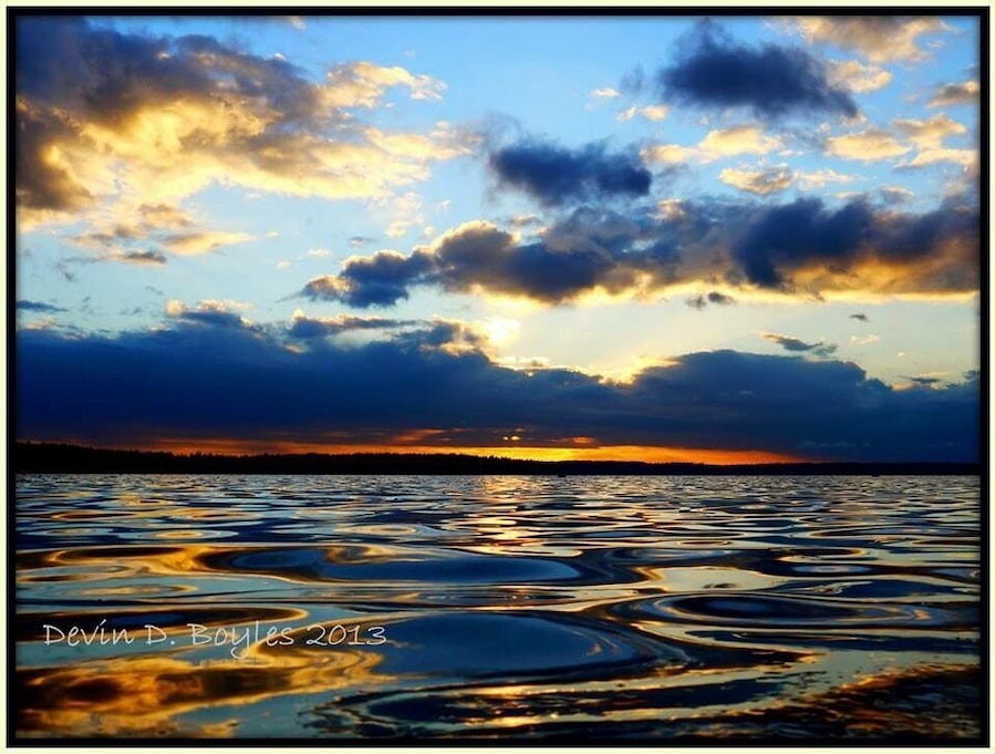 A sunset over a body of water with reflections of the sky.