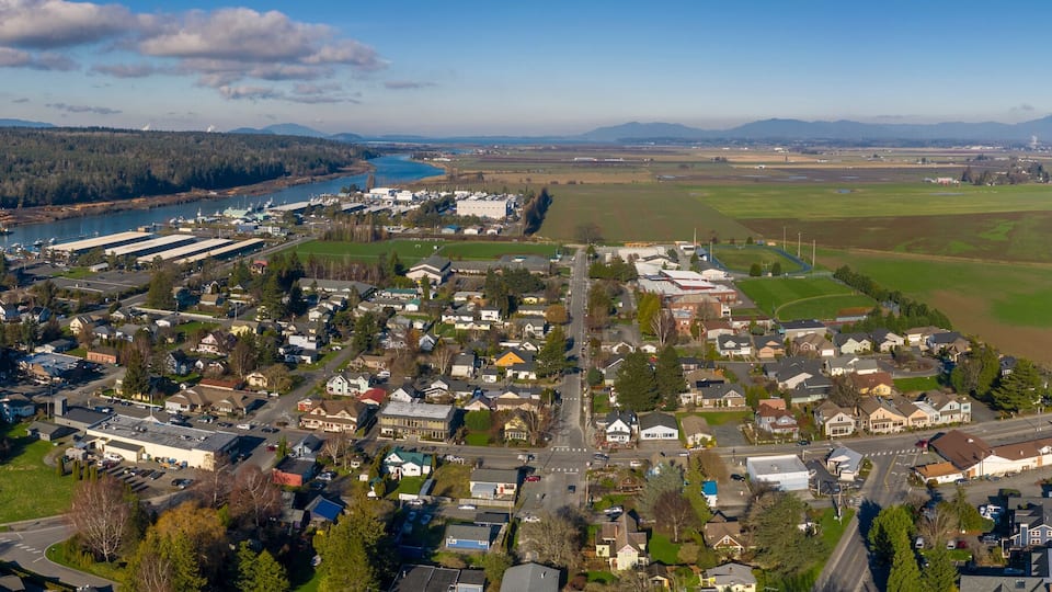 A town with a river, industrial buildings, and agricultural fields.