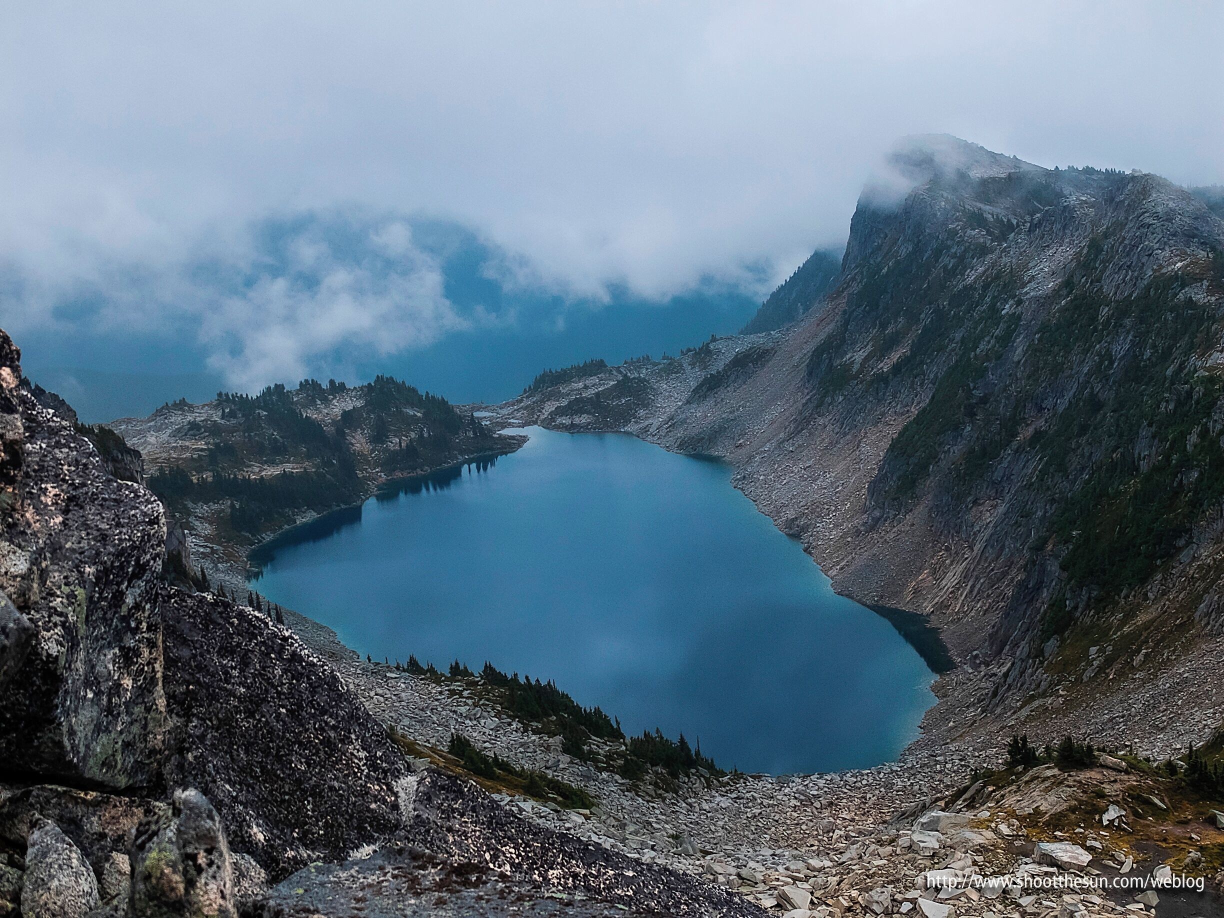 A mountain lake surrounded by rocky terrain and forested slopes.