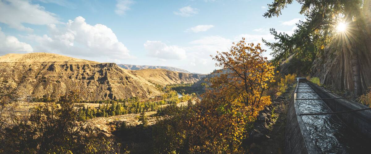 A mountainous landscape with a railway track, autumn foliage, and a clear sky.
