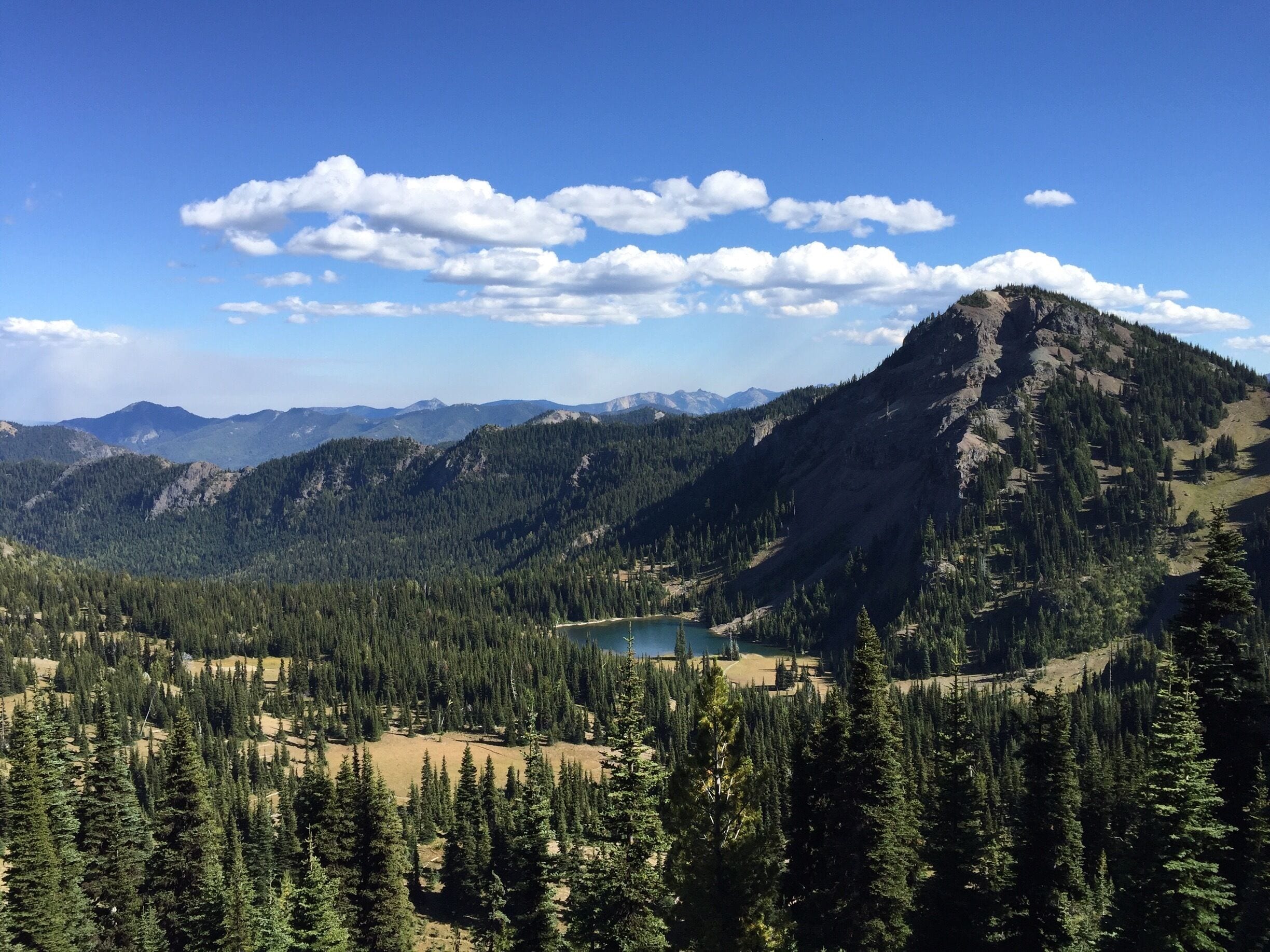 A mountain range with a lake and dense forests.