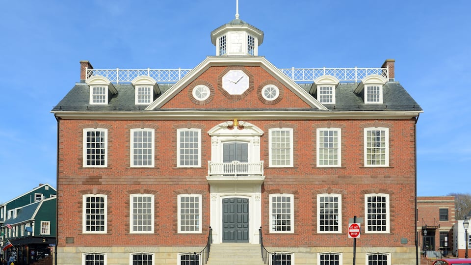 A large brick building with a clock tower, a balcony, and a "Do Not Enter" sign.
