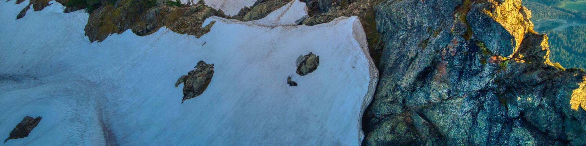Aerial view of a snowy rocky hill in the daytime