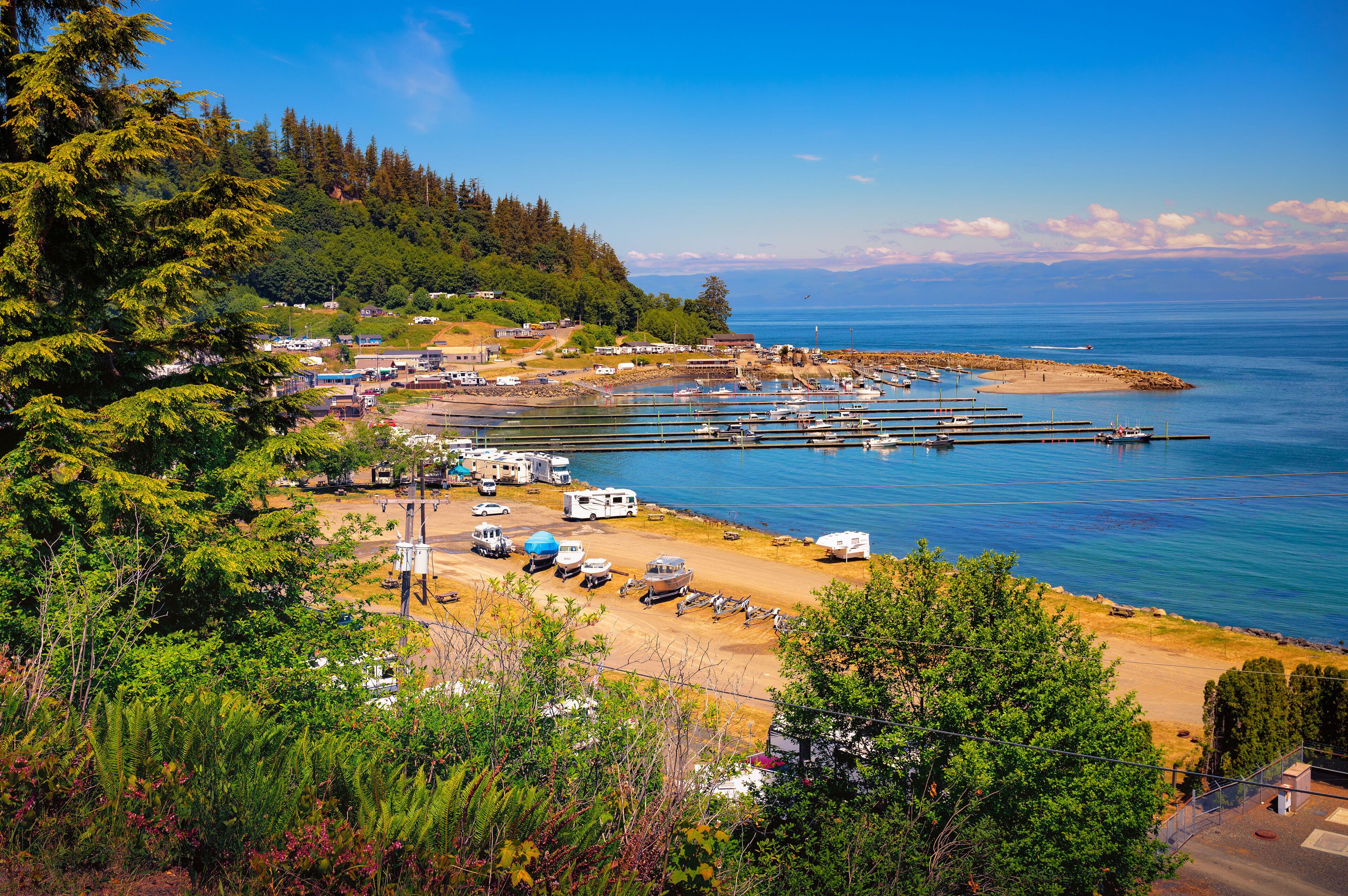 Aerial view of Sekiu Port with yachts, surrounded by by lush forests, capturing the scenic landscape of Washington State.