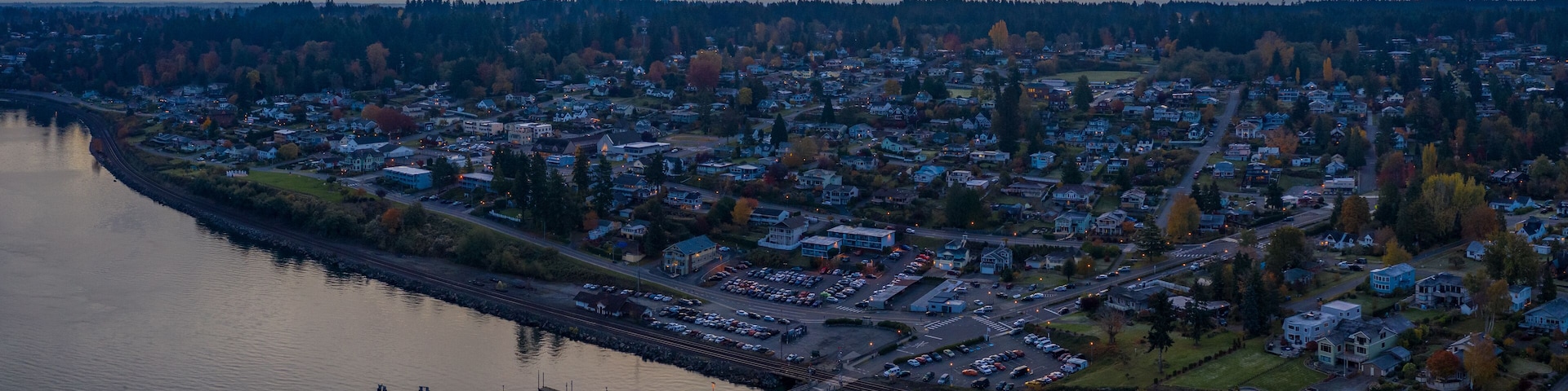 Un río con un puente, un embarcadero y un pueblo con casas y árboles.