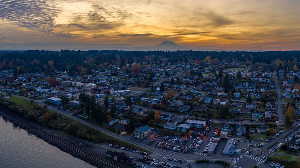 A town with a river on one side and a mountain in the background.