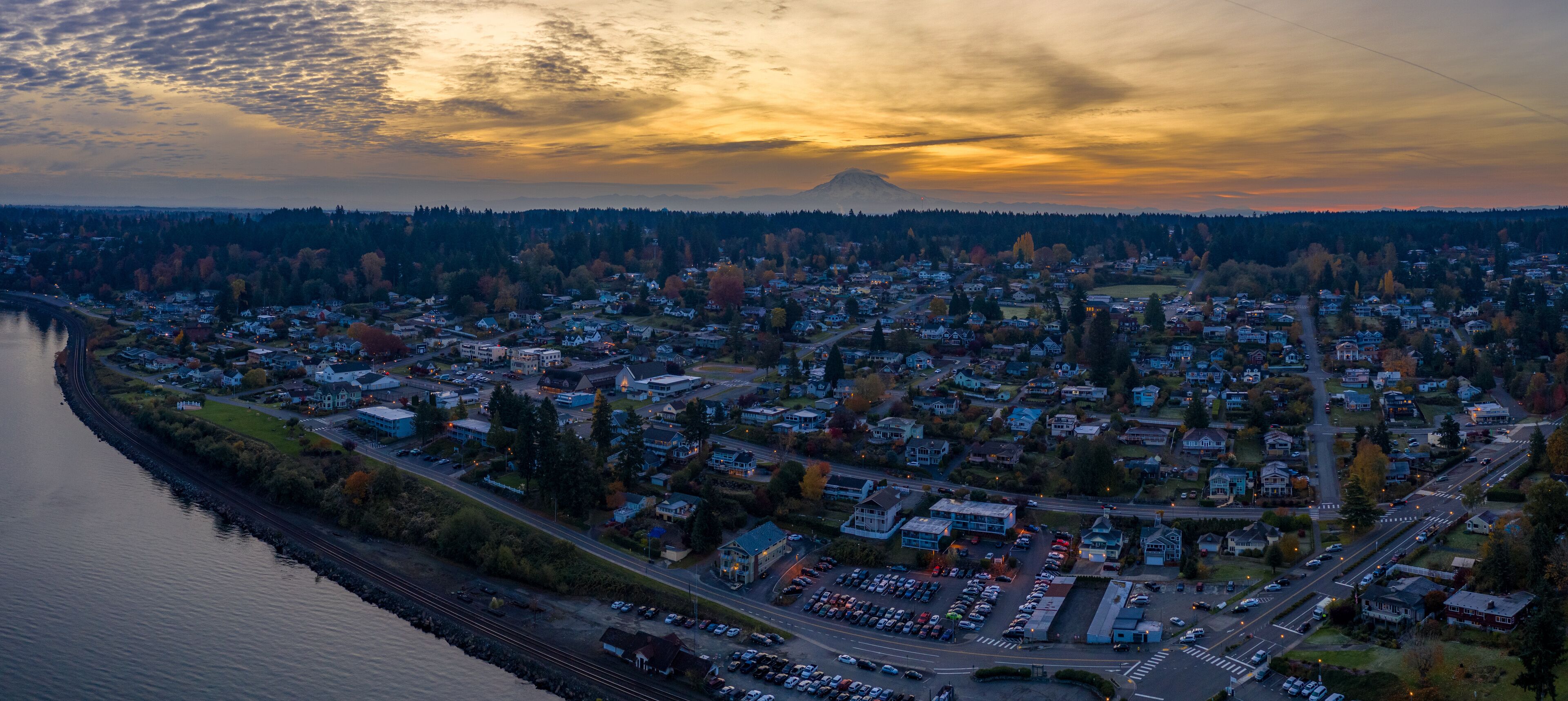 A town with a river on one side and a mountain in the background.