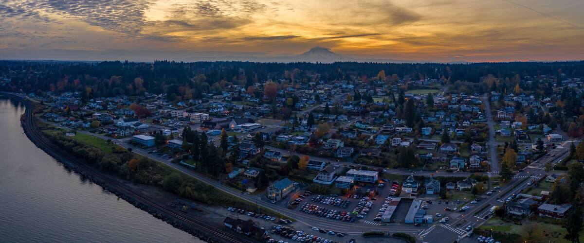 A town with a river on one side and a mountain in the background.
