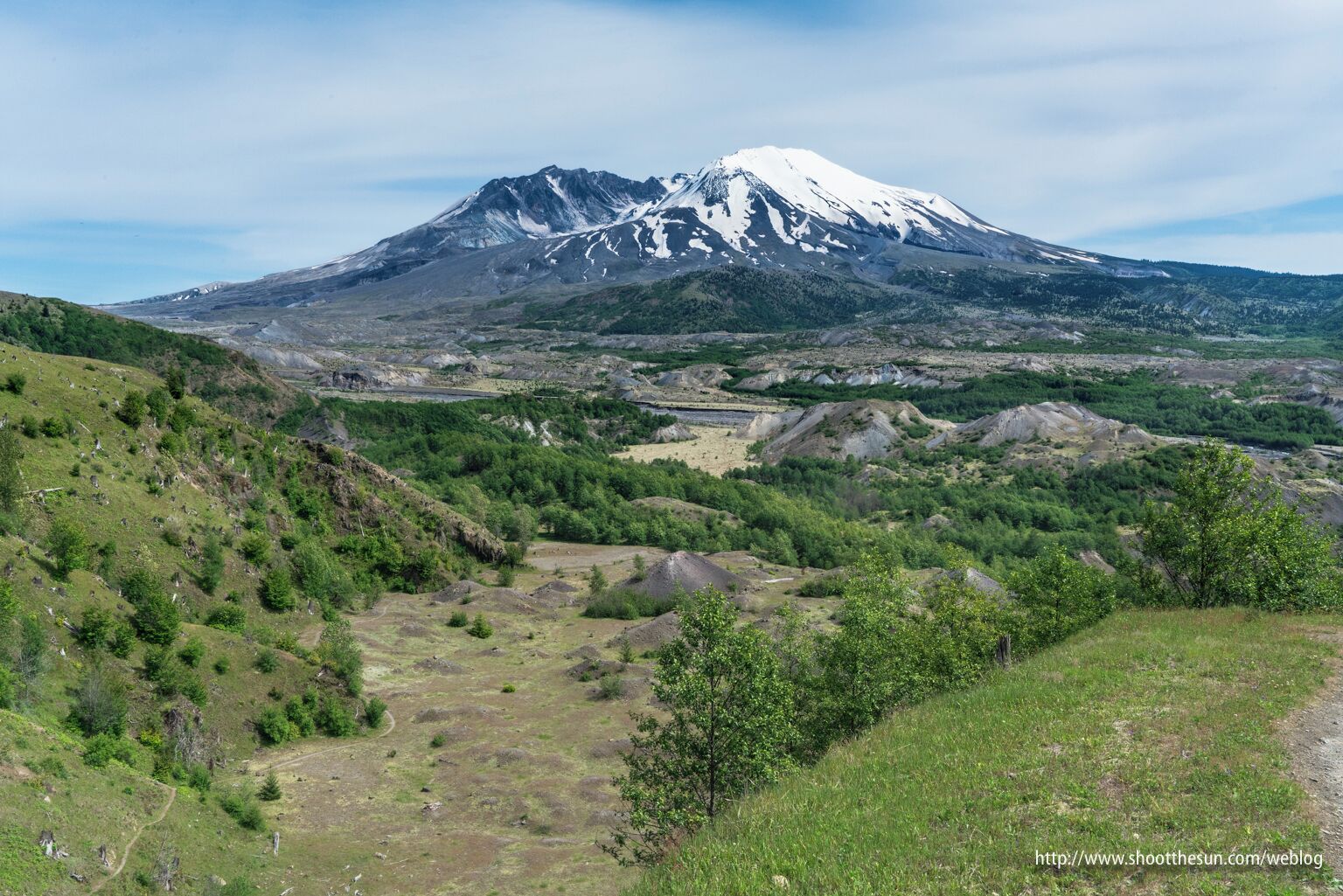 A snow-capped mountain, green valleys, and a clear sky.