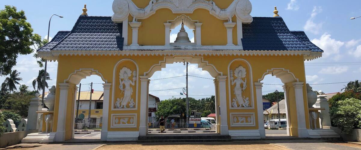 A yellow temple with intricate carvings and a blue roof.