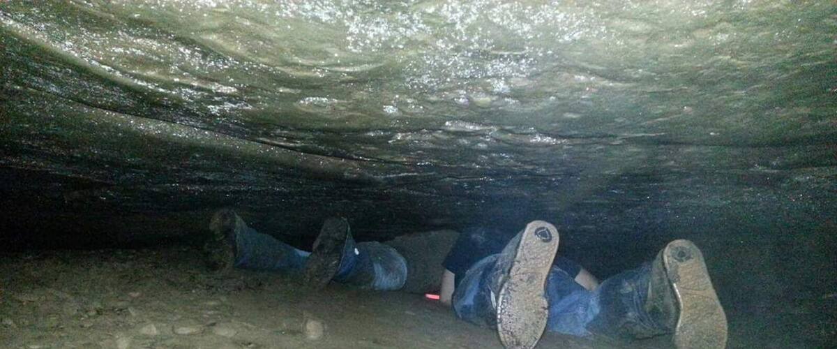 A cave interior with a rough, uneven floor and a narrow passageway.