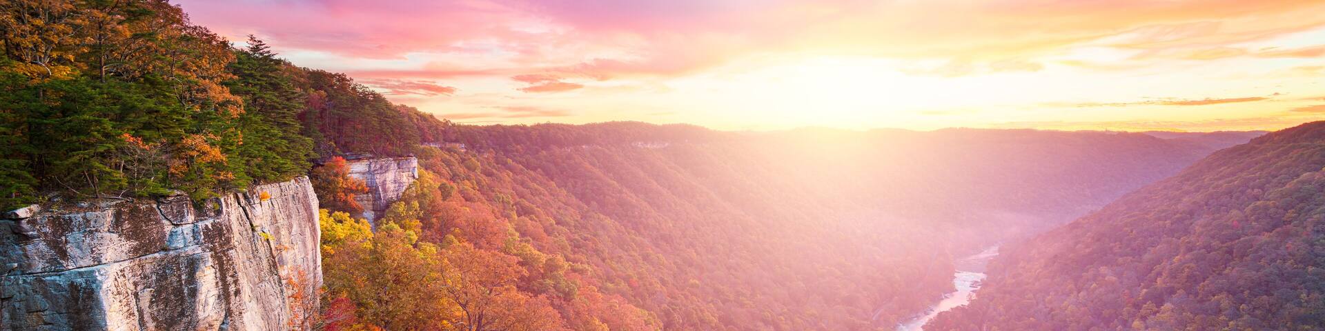 A canyon with a river, autumn foliage, and a rocky cliff.