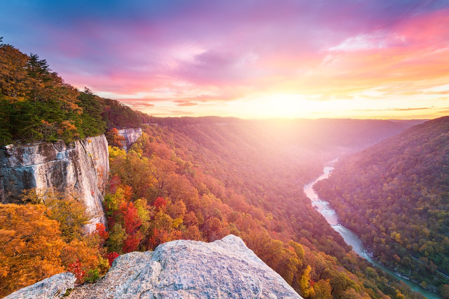 A canyon with a river, autumn foliage, and a rocky cliff.