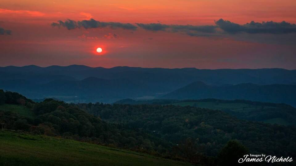 A sunset over a mountainous landscape with a visible sun.