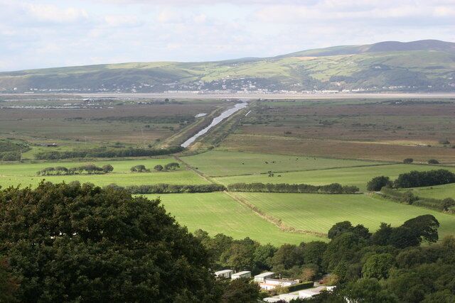 A rural landscape with fields, a road, and distant hills.