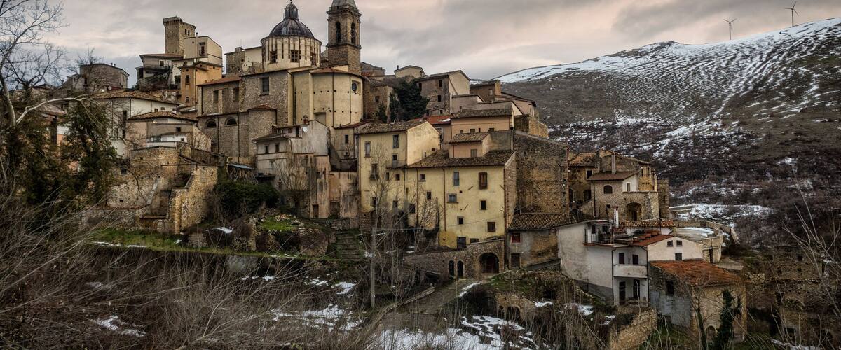 A historic town with a prominent church, a bell tower, and a castle-like structure on a hill.