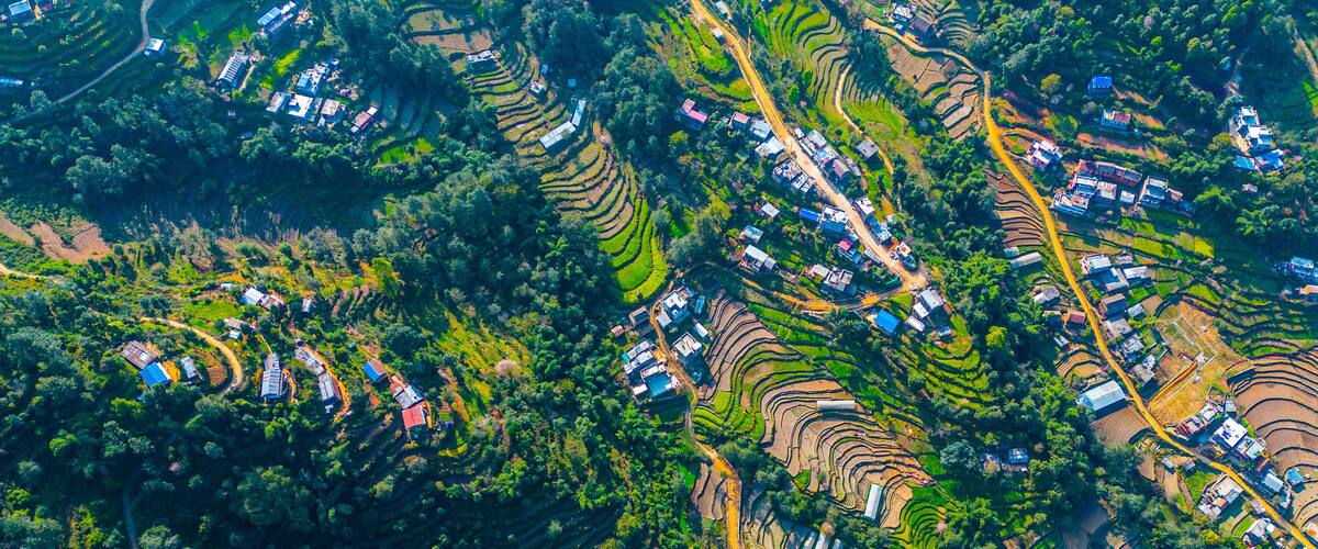 An aerial view of terraced rice fields with scattered houses and roads.