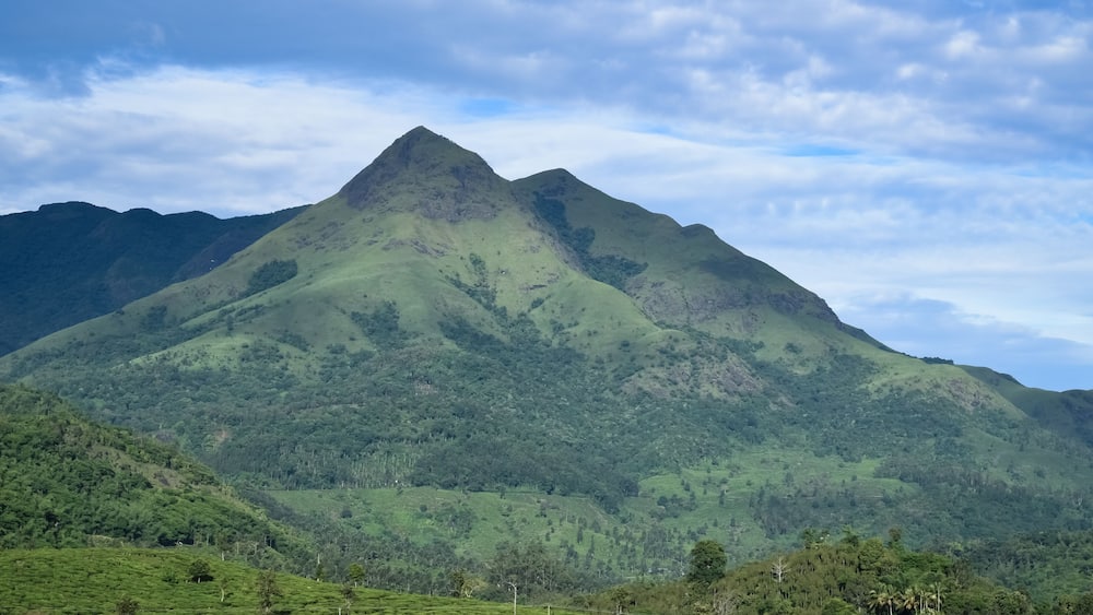 Une chaîne de montagnes aux collines verdoyantes et sous un ciel dégagé.