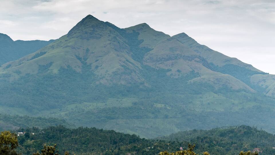 A mountain range with lush green valleys and scattered houses.