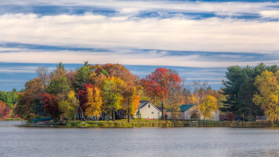 A lake with autumn-colored trees and a house by the water.