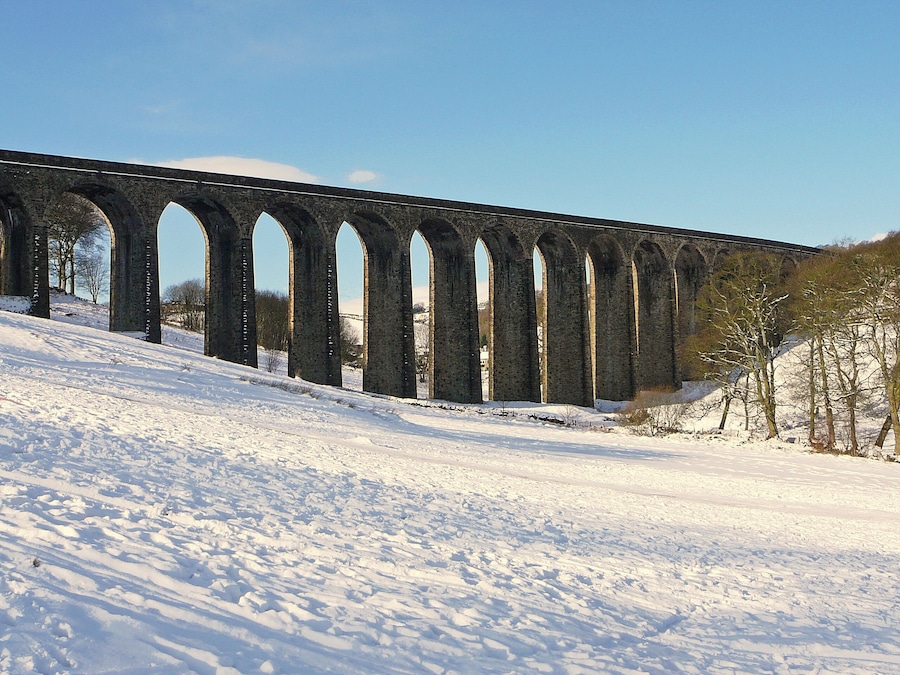 A snow-covered railway viaduct with multiple arches.
