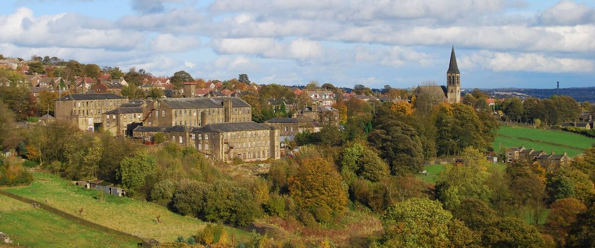 A town with historic buildings, a prominent church tower, and rolling green hills.