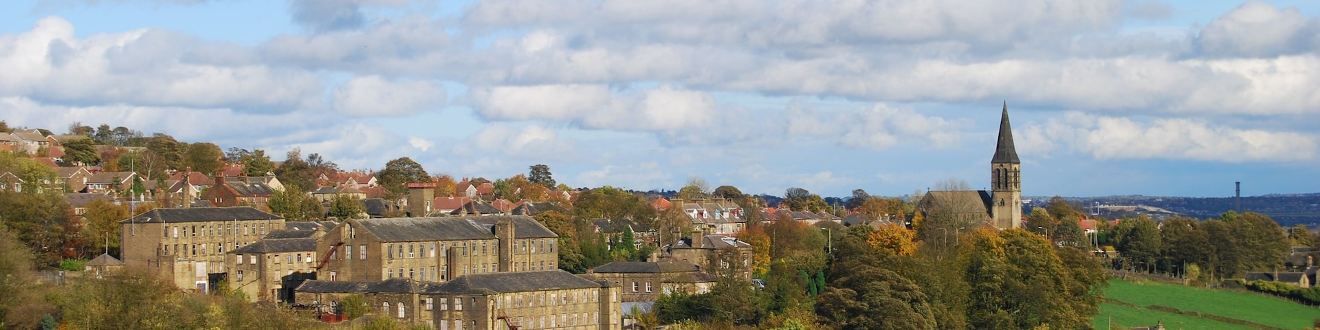 A town with historic buildings, a prominent church tower, and rolling green hills.