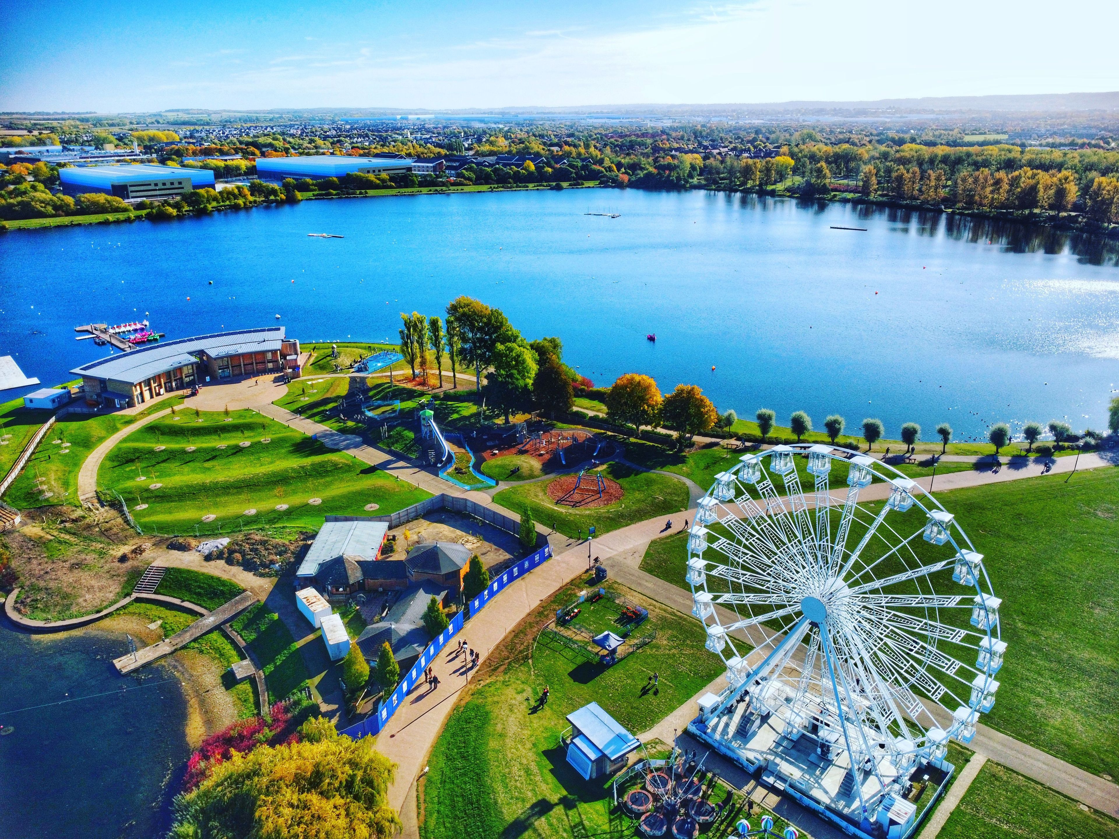 A large body of water with a Ferris wheel, a playground, and a building with a blue roof.