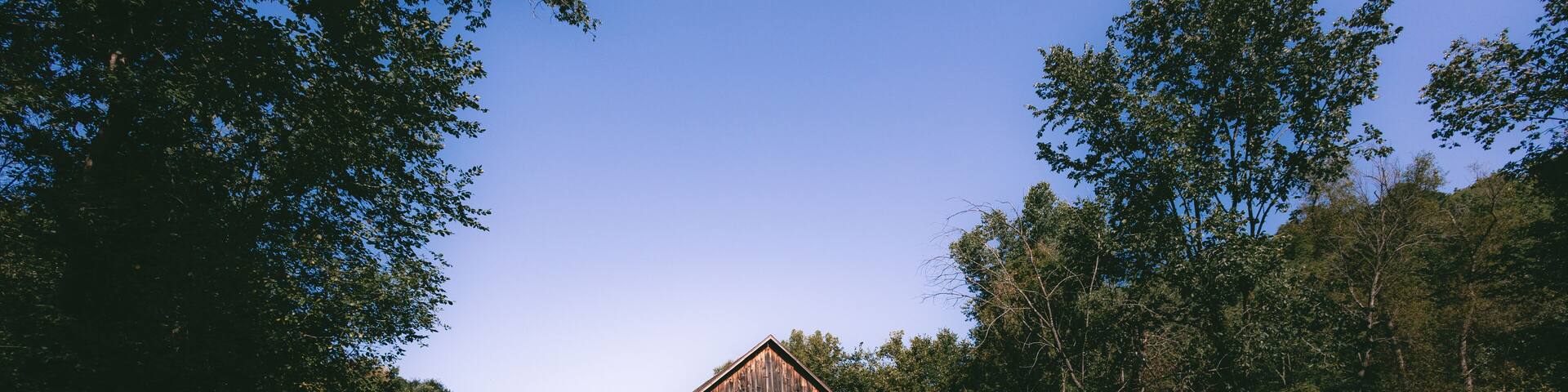 A wooden barn surrounded by lush greenery and trees.