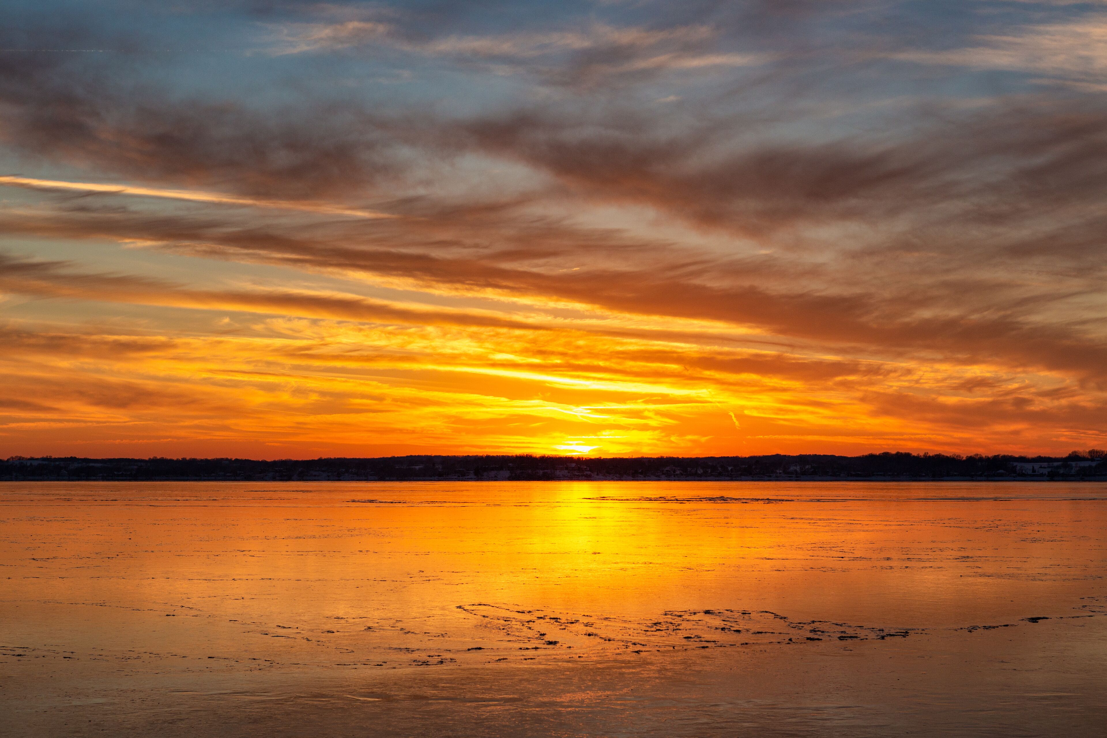 A sunset over a frozen lake with a city skyline in the background.