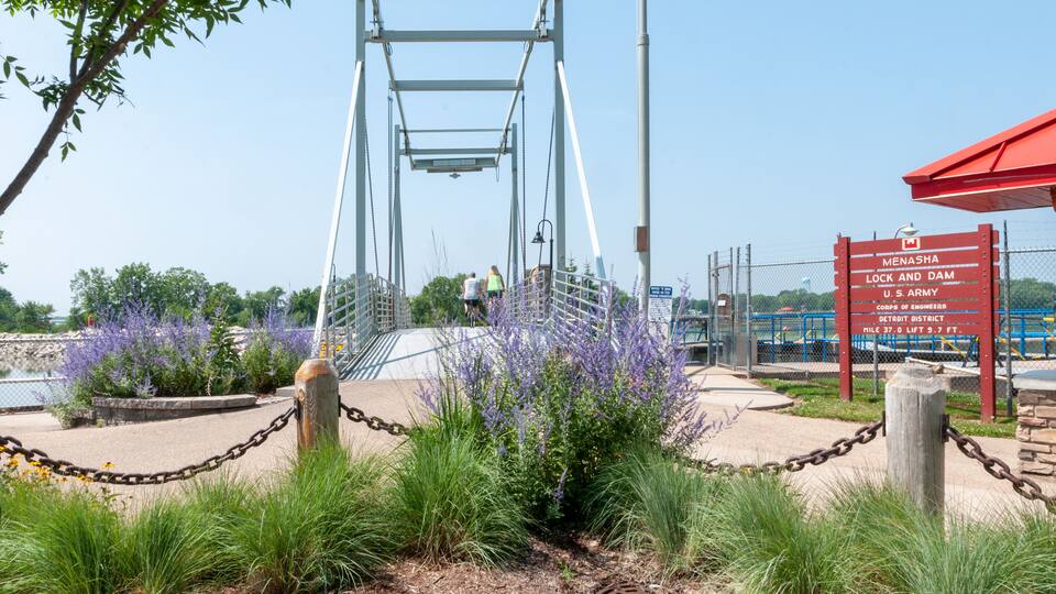 A pedestrian bridge with a sign indicating it is part of the U.S. Army Corps of Engineers' Detroit District, spanning 37.0 miles and 5.7 feet high.