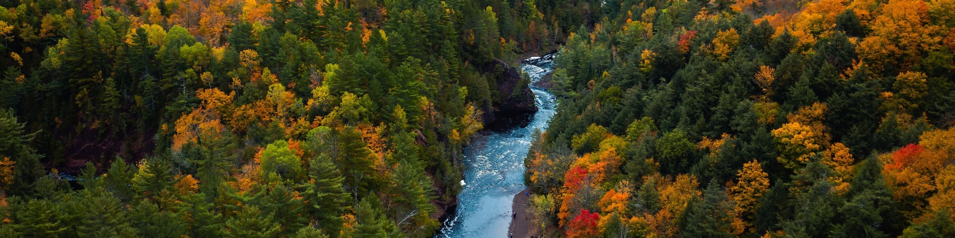 A river winding through a forest with autumn foliage.