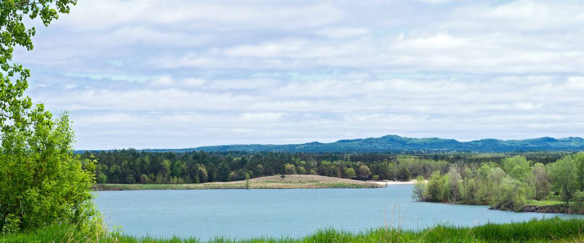 A lake surrounded by lush greenery and distant hills.