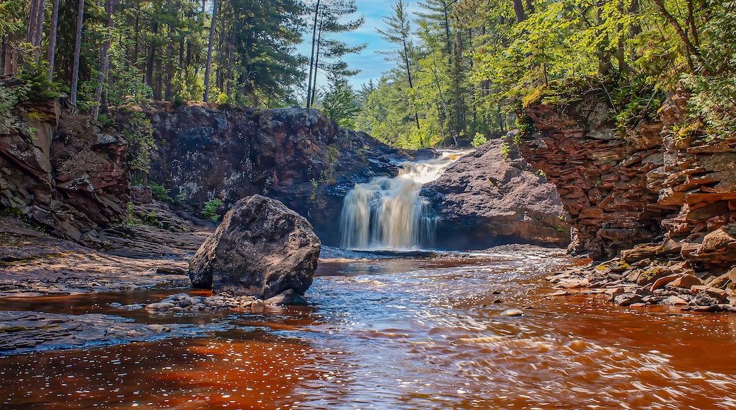 A waterfall cascading over a rocky ledge surrounded by dense forest.