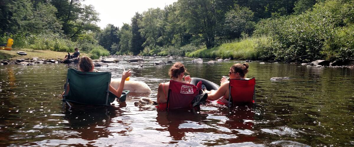 Three people in canoes on a river surrounded by trees.