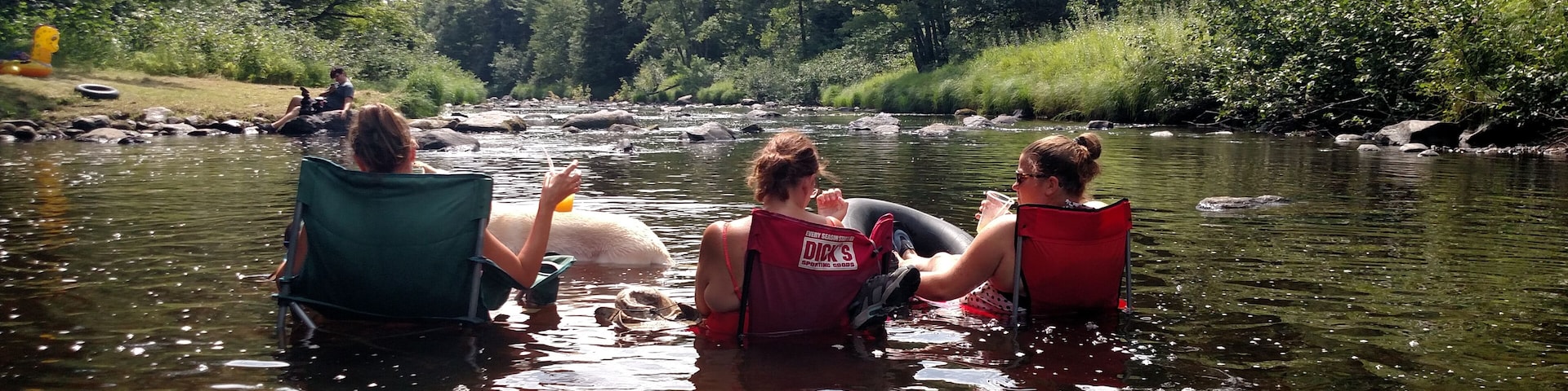 Three people in canoes on a river surrounded by trees.