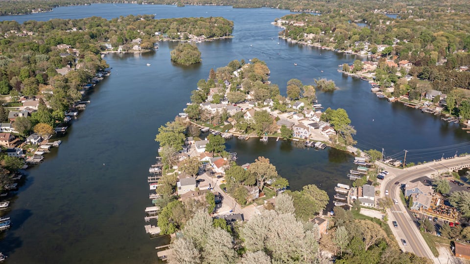 An aerial view of a river town with docks, houses, and trees along the water.