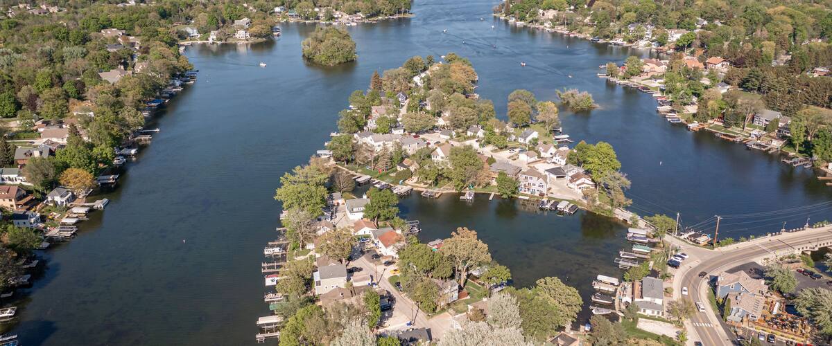An aerial view of a river town with docks, houses, and trees along the water.