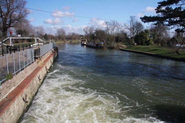 River Cam at Baits Bite Lock The rushing water is spilling from the weir, looking downstream from the footbridge across the river.