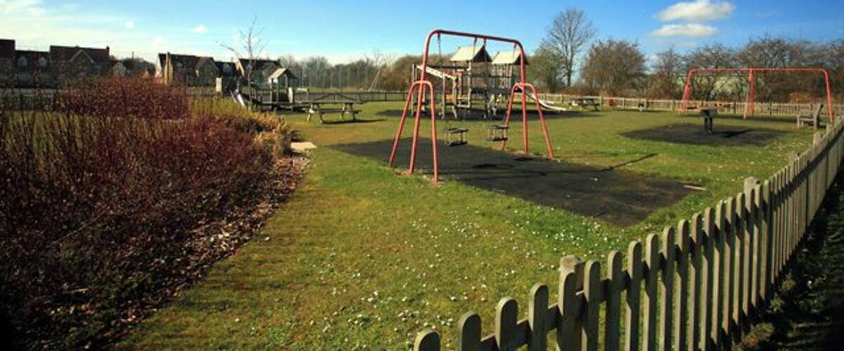 A playground with swings and a fenced area.