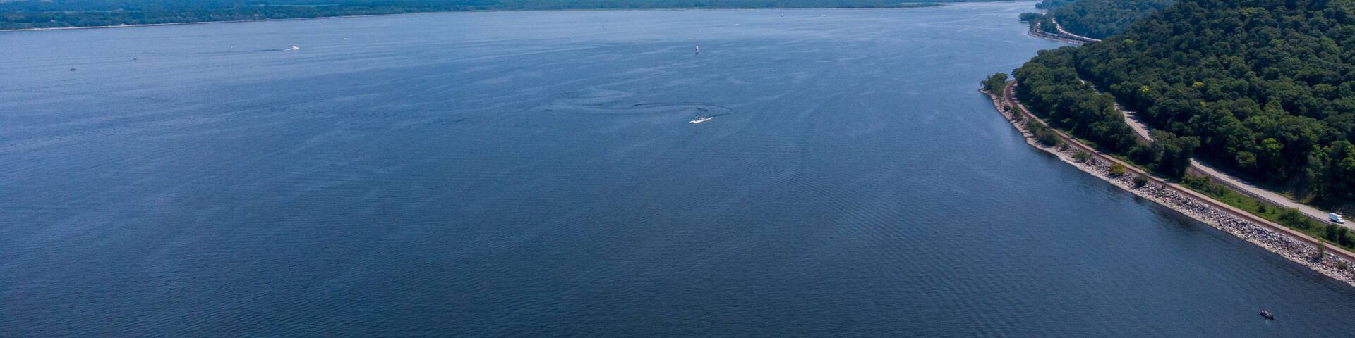 A large body of water with a forested coastline and a distant mountain range.