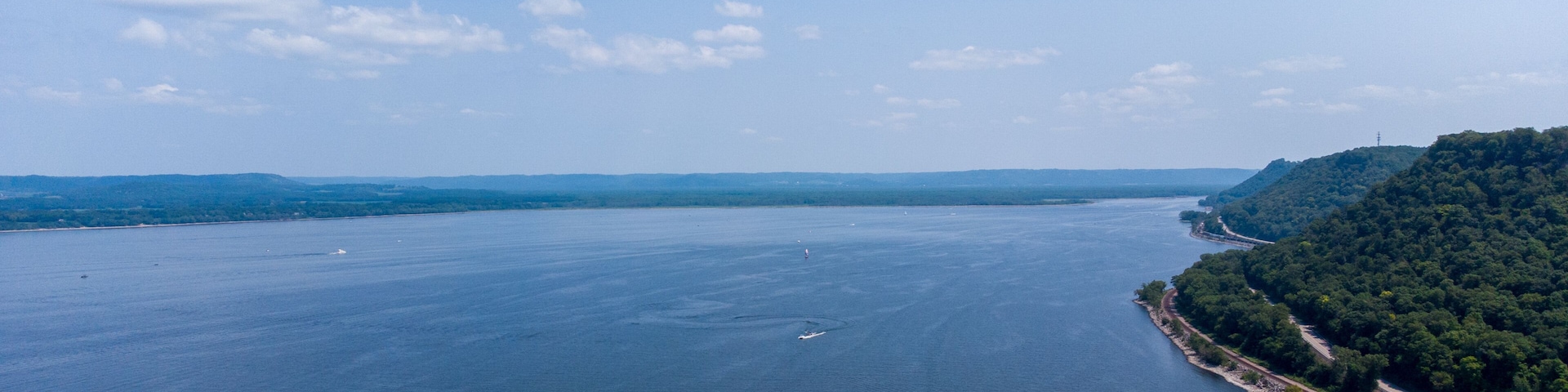 A large body of water with a forested coastline and a distant mountain range.