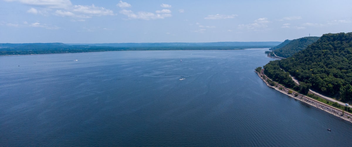 A large body of water with a forested coastline and a distant mountain range.