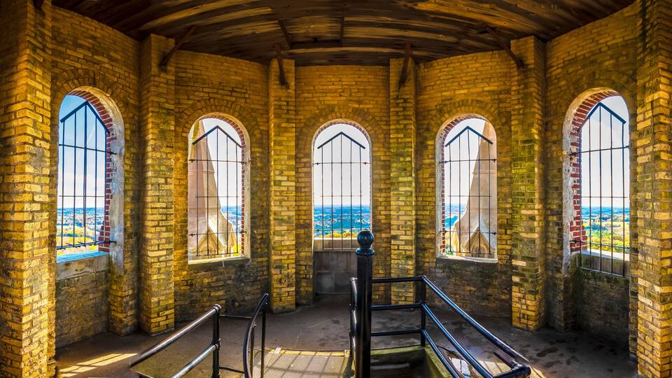 An arched brick interior with large windows and a wooden ceiling.