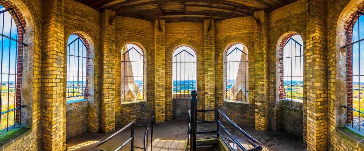 An arched brick interior with large windows and a wooden ceiling.