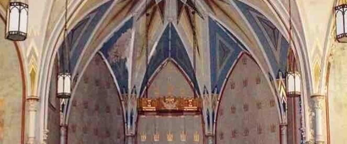 A church interior with Gothic arches, a central altar, and religious statues.