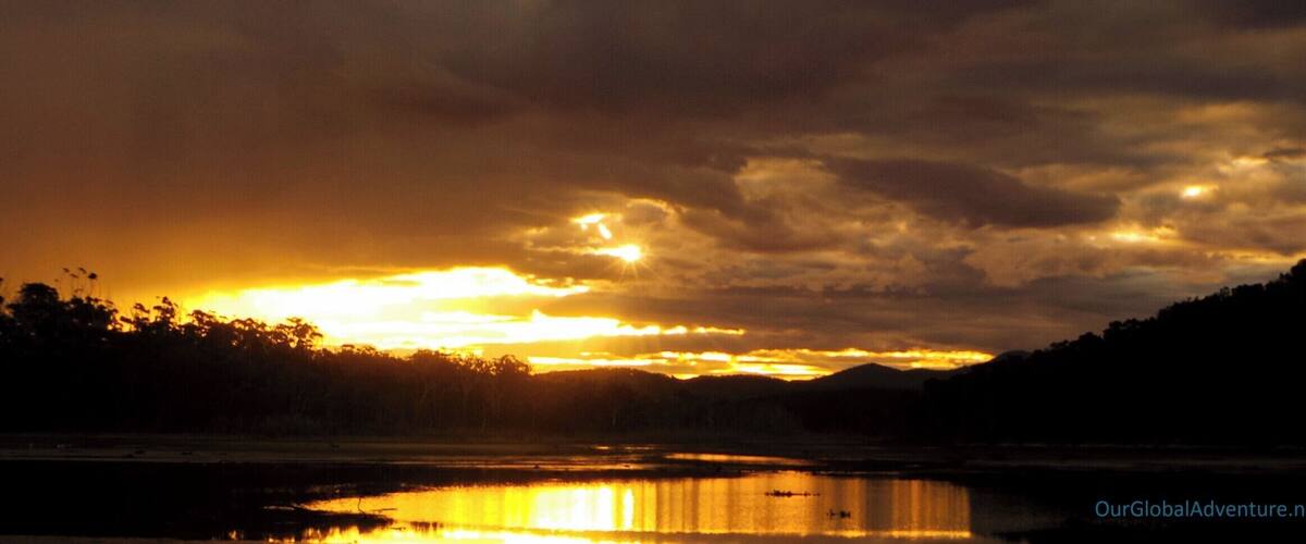 A sunset over a lake with mountains in the background.
