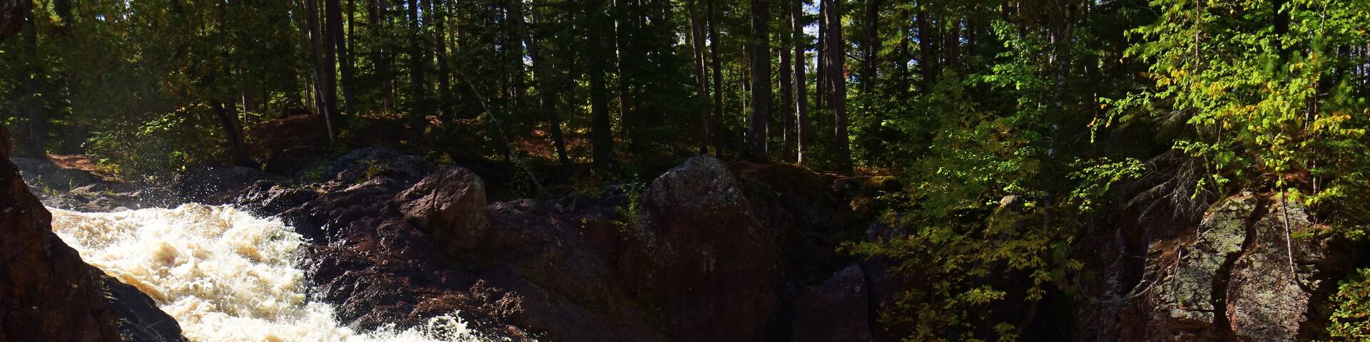 A waterfall cascading over rocks in a forested area.