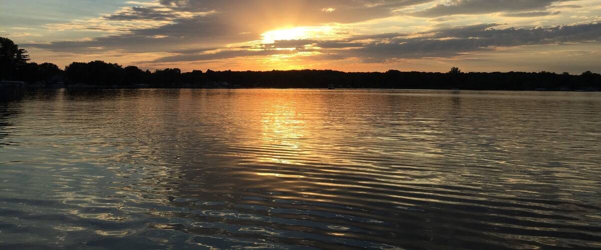 A sunset over a calm lake with reflections of the sky.