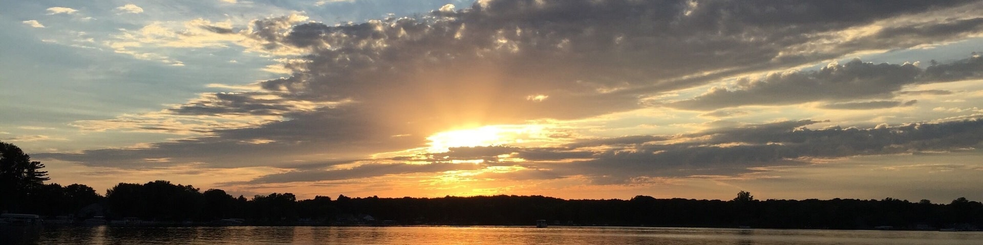 A sunset over a calm lake with reflections of the sky.